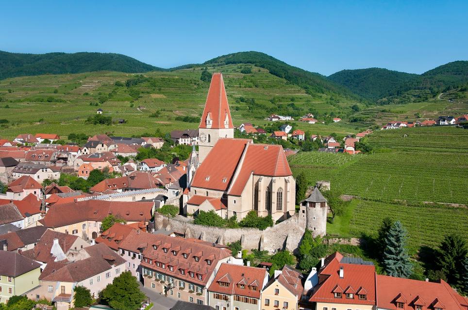 Luftaufnahme von Weissenkirchen mit Wehrkirche und Weingärten im Sommer.