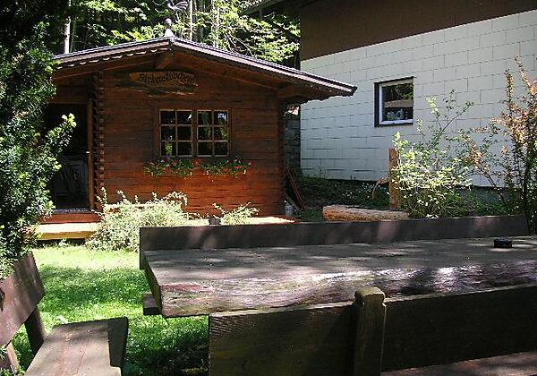 Holzhütte und -sitzgruppe im Garten