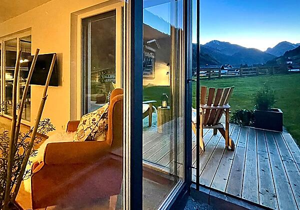 Fensterfront mit Blick auf Garten und Bergpanorama